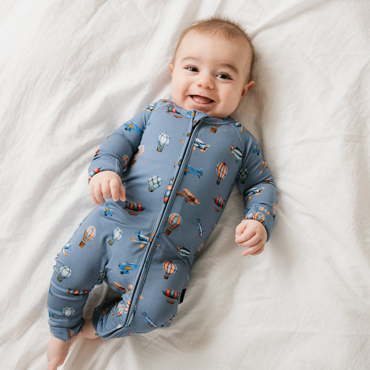 Smiling baby in a printed zippered romper